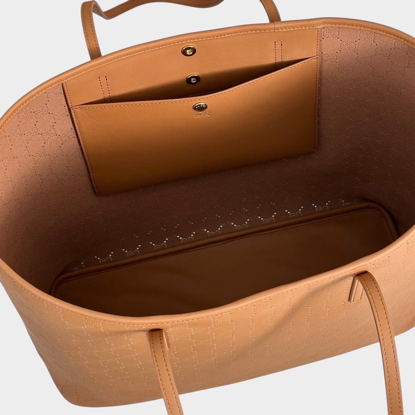 Zebass GUCCI tan leather tote bag interior with laser-cut monogram pattern, snap-button closure, and slip pocket.