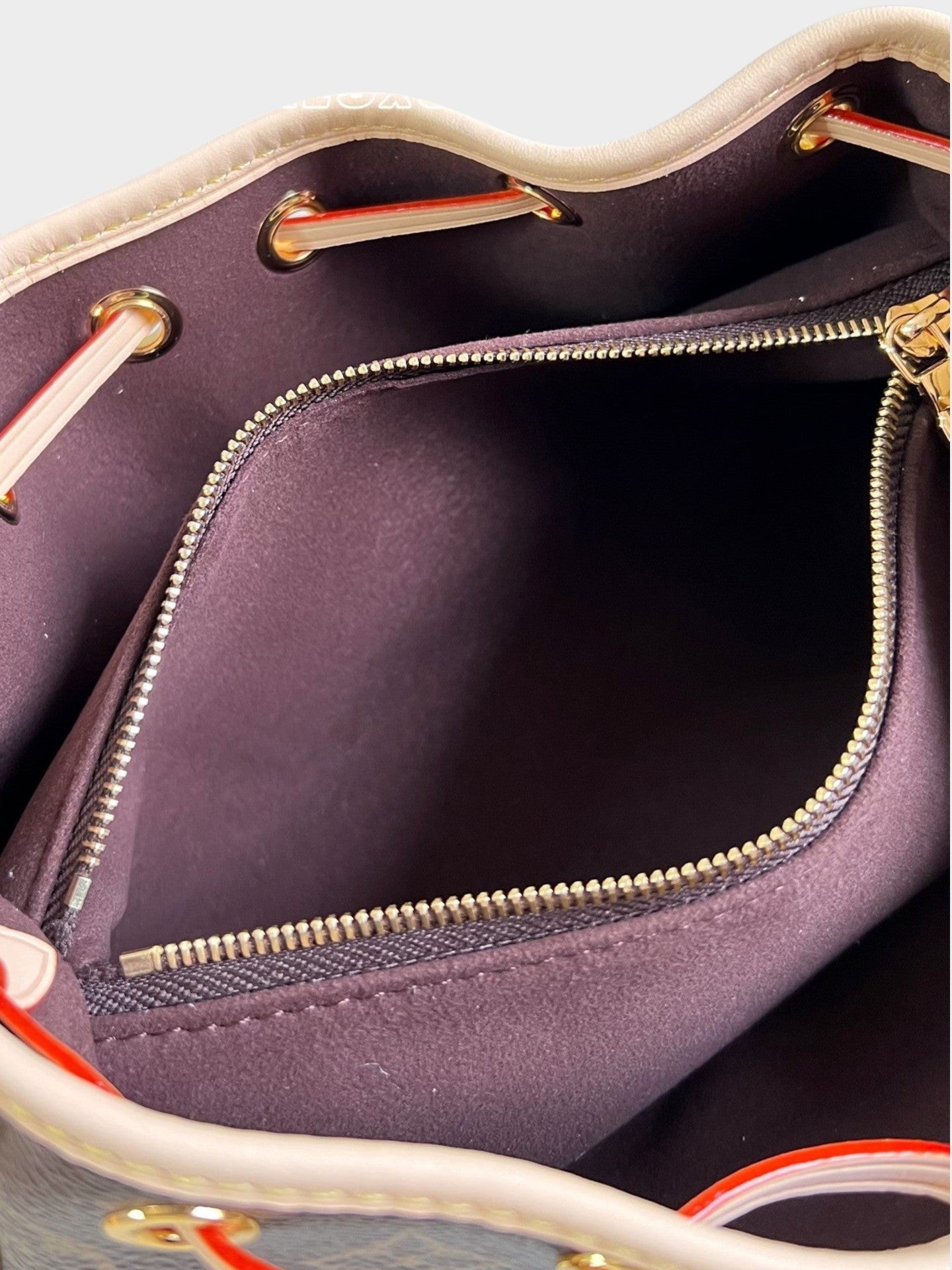 Zebass Louis Vuitton monogram canvas bucket bag interior with dark brown fabric lining and gold-tone zipper pocket