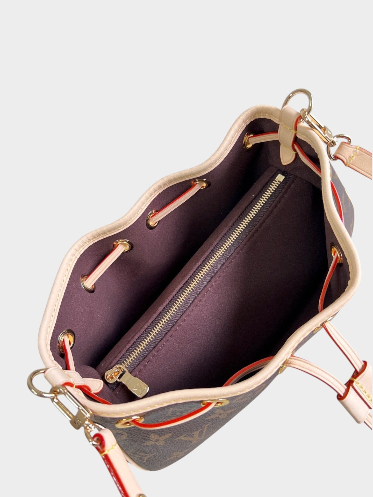 Zebass Louis Vuitton monogram bucket bag interior with dark brown fabric lining, gold hardware, and zippered pocket.