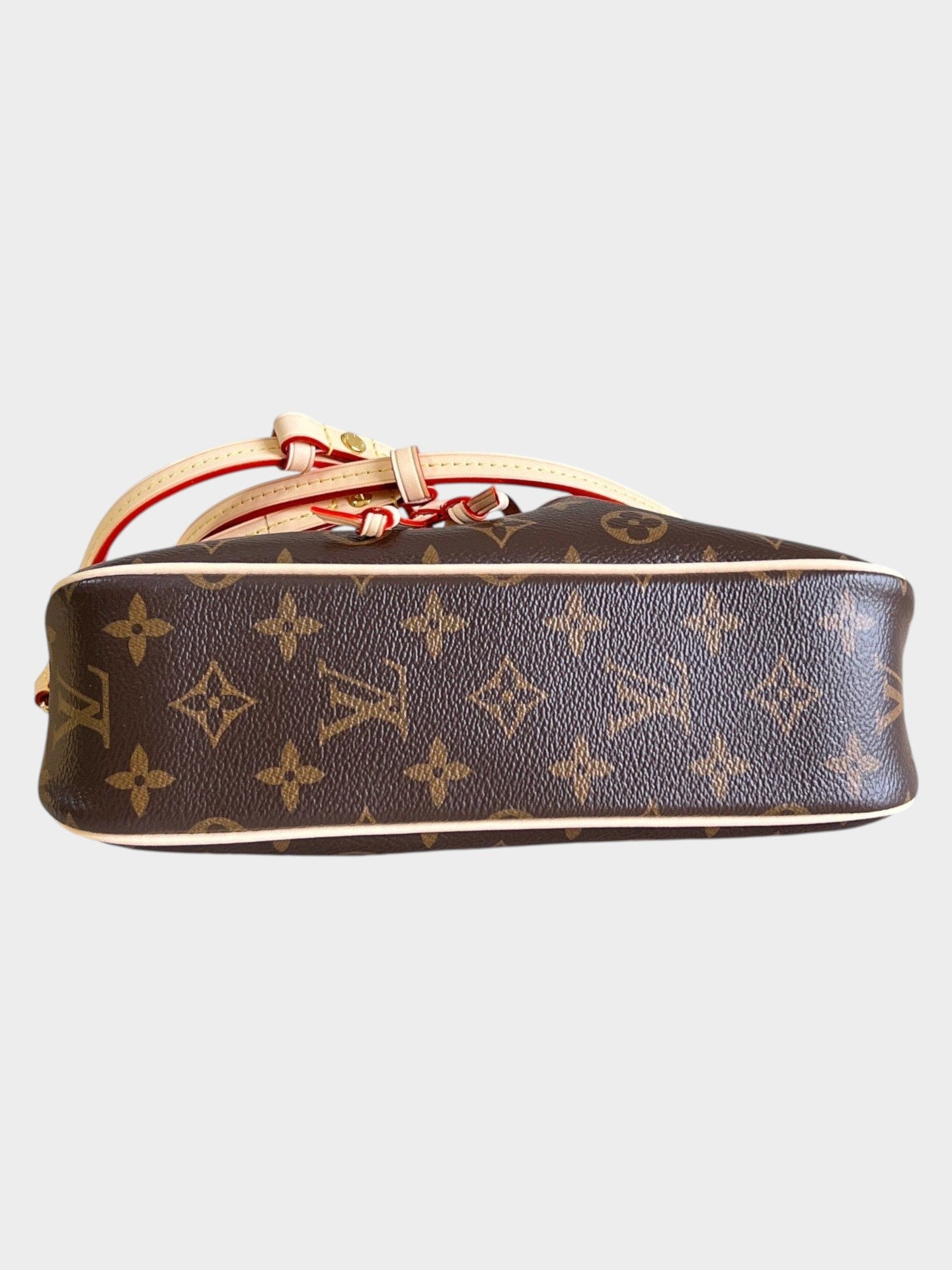 Zebass monogram canvas bucket bag with light leather trim and red edge detailing, shown from a side angle.